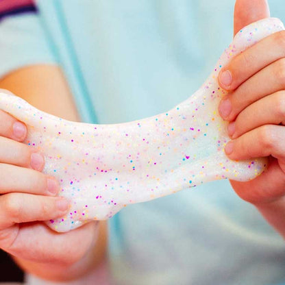 Two hands stretching white white putty with multicolor glitter.